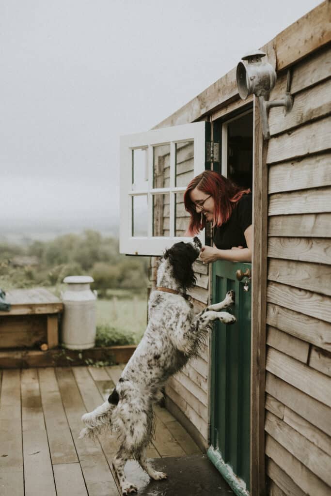 Femme qui joue avec son chien à côté d'une cabane