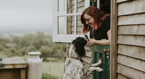 Femme qui joue avec son chien à côté d'une cabane