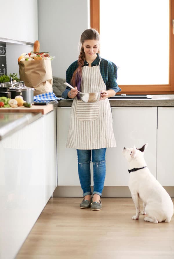 une femme qui cuisine et son chien la regarde