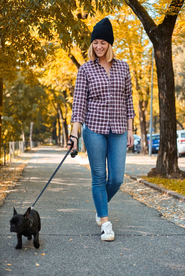 chiot noir en promenade dans un parc avec sa propriétaire