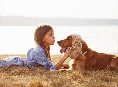 Chien avec une petite fille qui se font un câlin face à la mer