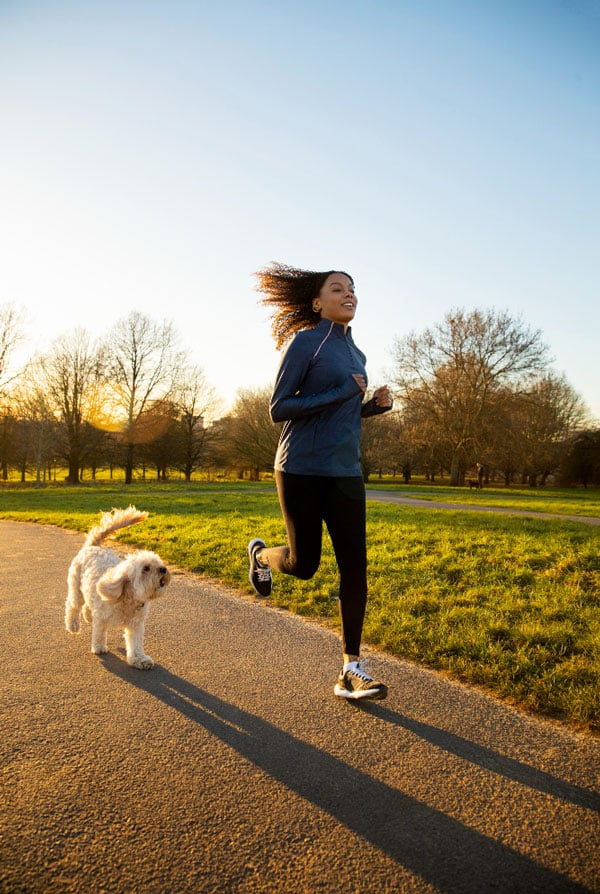 Un chien qui court dans un parc avec sa propriétaire