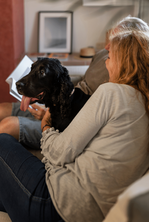 Chien noir assis avec ses maitres sur le canapé